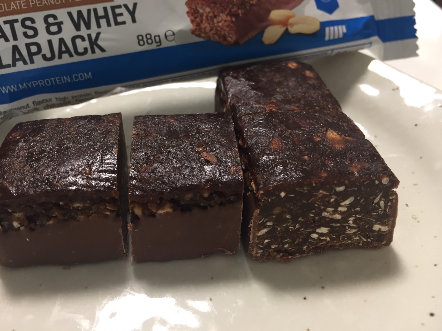 OATS & WHEY FLAPJACK(オーツ & ホエイ)「CHOCOLATE PEANUT FLAVOUR(チョコレートピーナッツ味)」を包丁で切った断面