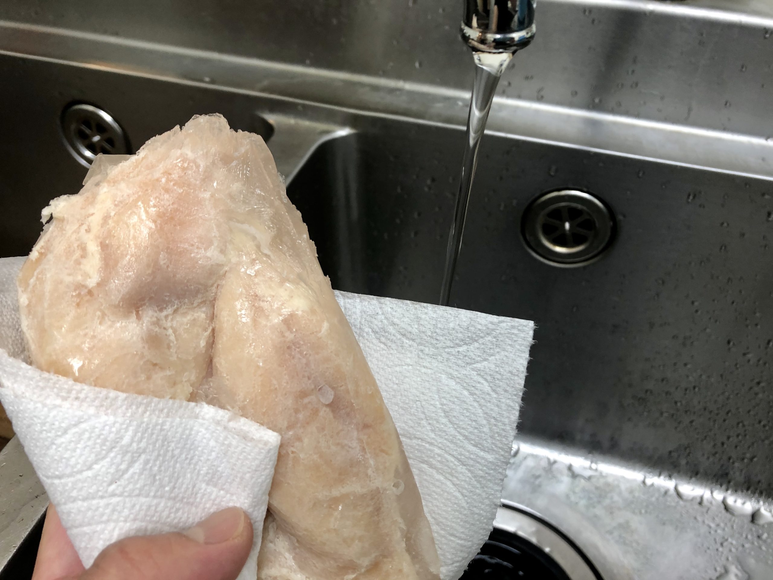 冷凍状態で袋から鶏ハムを出し、固まった水分やゼラチン部分を拭き取ります。